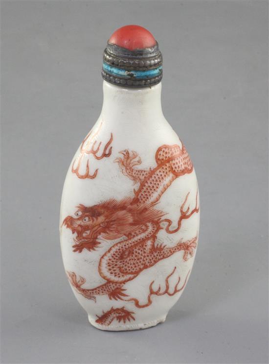 A Chinese iron red enamelled dragon snuff bottle, 19th century, height 7.6cm excl. coral and enamelled silver stopper